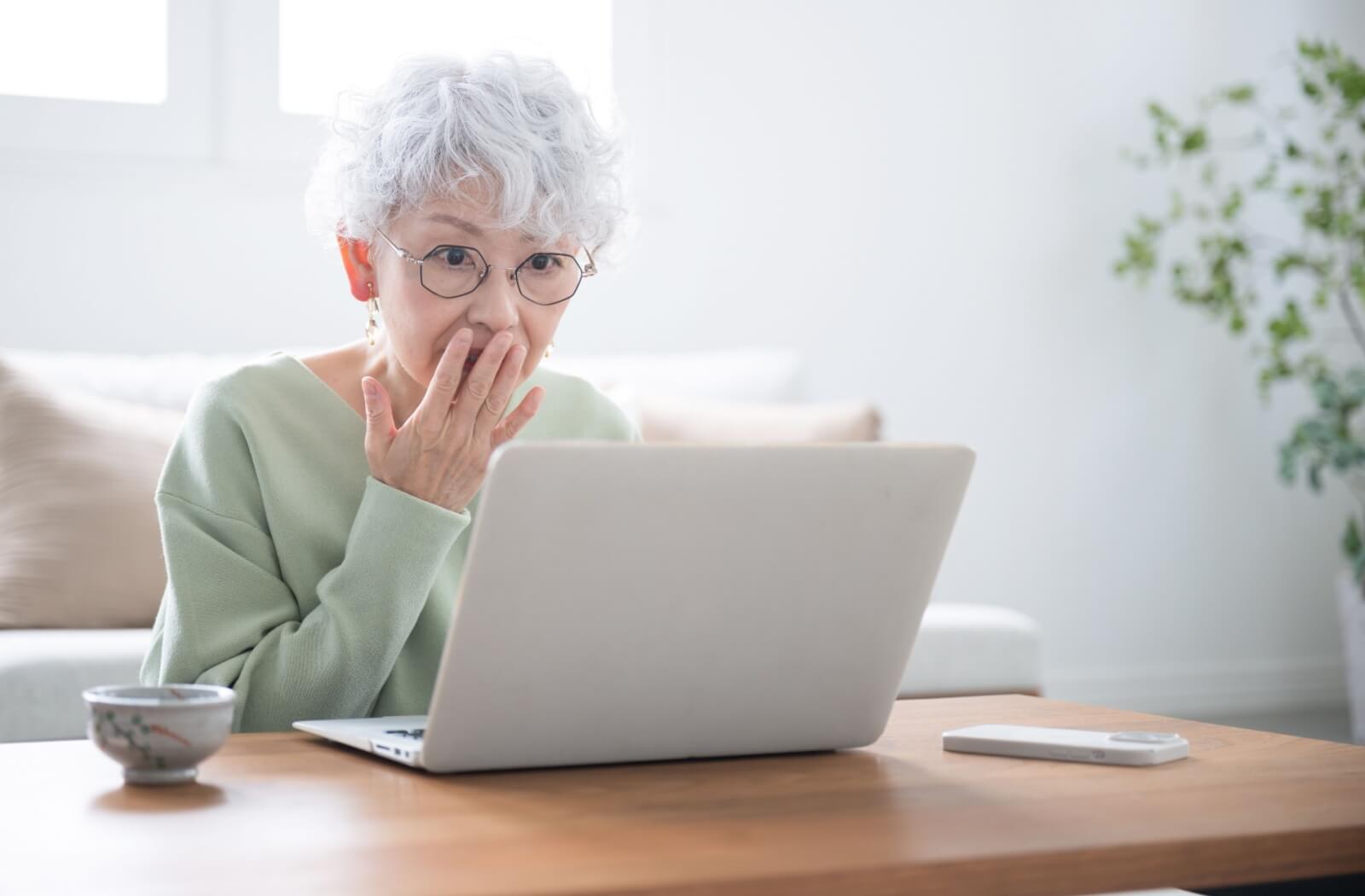 A concerned older adult looking up the signs of dementia on their laptop.