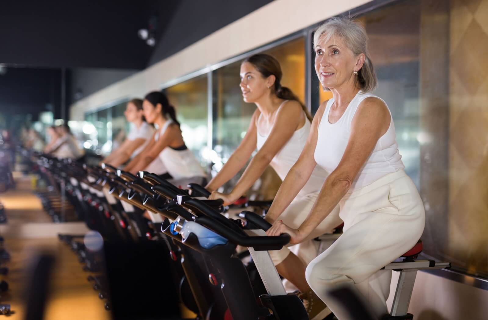 Older adult cycling in fitness class with others to build strength and improve balance through regular exercise